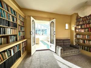 uma biblioteca com estantes de livros e um sofá e uma cadeira em Large Georgian house in heart of Exeter em Exeter