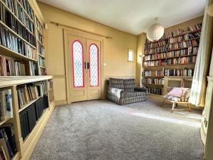 uma biblioteca com uma cadeira, uma porta e livros em Large Georgian house in heart of Exeter em Exeter