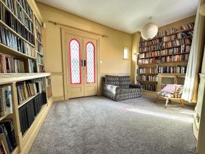 a library with a chair and a door and books at Large Georgian house in heart of Exeter in Exeter +14 photos
