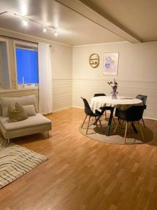 - un salon avec une table, des chaises et un canapé dans l'établissement Leilighet med god utsikt, à Tromsø