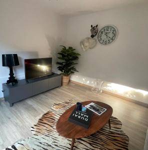 a living room with a table and a clock on the wall at Piso con jardín en Liencres in Liencres