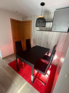 a black dining room table with black chairs and a red rug at Piso con jardín en Liencres in Liencres