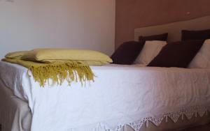 a bed with white sheets and a yellow pillow on it at Castellabate House in Santa Maria di Castellabate