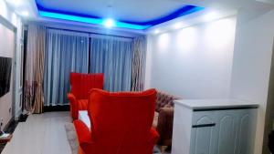 a living room with red chairs and a blue ceiling at the perfect affordable apartments in Nairobi