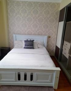 a white bed with a pillow on top of it at the perfect affordable apartments in Nairobi