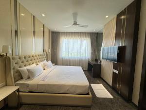 een slaapkamer met een groot bed en een televisie bij HOTEL CARNIVAL in Parbhani