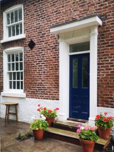 uma casa de tijolos com uma porta azul e vasos de plantas em Welcoming luxury in a Grade II listed building em Chester
