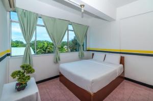 a bedroom with a bed and a large window at Sutera Inn Inanam in Kota Kinabalu