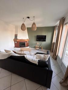 ein Wohnzimmer mit einem schwarzen Sofa und einem Kamin in der Unterkunft LA BELLE ESCALE in Belfort