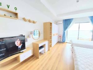uma sala de estar com uma televisão de ecrã plano e uma cama em CĂN HỘ TMS 28 NGUYỄN HUỆ QUY NHƠN em Quy Nhon
