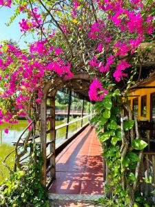 un jardín con flores rosas en un puente de madera en TINA LAKESIDE AO ĐÔI Homestay Phước Hải, en Hội Mỹ