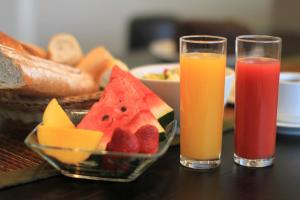 two glasses of juice and a bowl of fruit on a table at Hotel Confiance Prime Batel in Curitiba