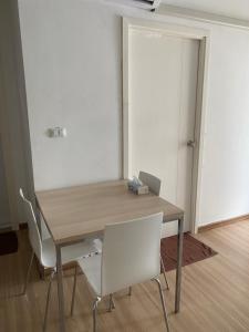 uma mesa de madeira com duas cadeiras brancas e uma porta em 2BR Apartment em Banguecoque