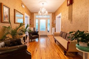 a living room with leather furniture and a chandelier at The Dawson House Bed & Breakfast in Charlottetown