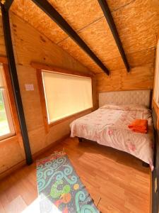 ein kleines Schlafzimmer mit einem Bett und einem Fenster in der Unterkunft Cabaña El Polux, ruta x-671 in Coihaique