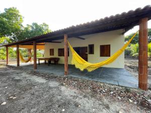 a house with a hammock in front of it at Casa na lagoa azul in Cruz