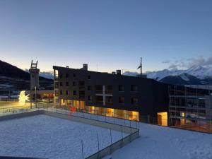 a building with a snow covered roof with mountains in the background at Monolocale sulle piste da sci in Pila
