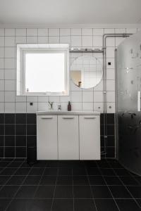 a white bathroom with a sink and a window at Vetteberget Lagenheten in Fjällbacka