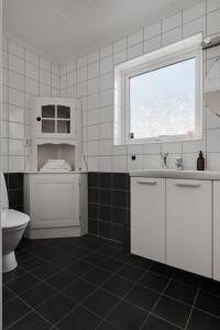 a white bathroom with a toilet and a window at Vetteberget Lagenheten in Fjällbacka