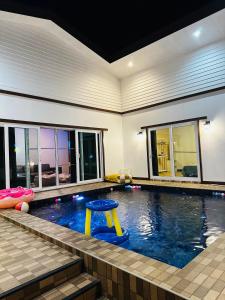 una piscina con un taburete amarillo. en GoodDay Poolvilla UdonThani บ้านพูลวิลล่ากู๊ดเดย์ อุดรธานี, en Udon Thani