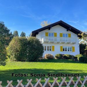 ein weißes Haus mit gelben Fenstern und einem Zaun in der Unterkunft Einzigartige Auszeit mit Bergblick in Bad Tölz in Bad Tölz