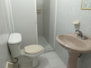 a white bathroom with a toilet and a sink at La Sirenita in Veracruz