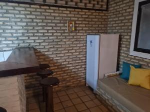 a kitchen with a refrigerator and a couch in a room at Porto do Sol - Chalé 25 in Pipa