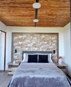 a bedroom with a large bed with a stone wall at Verdes Hábitat Glamping in Palestina