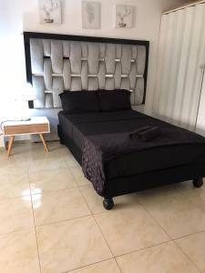 um quarto com uma grande cama preta e uma mesa em San Alejo em Tuluá