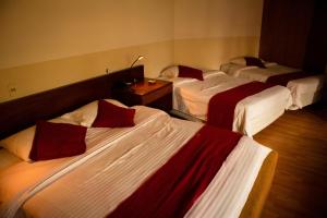 um quarto de hotel com três camas com lençóis vermelhos e brancos em Hotel Oberland em La Paz