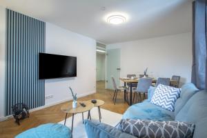 ein Wohnzimmer mit einem blauen Sofa und einem TV in der Unterkunft CoView - ruhige Design Wohnung - 2 Schlafzimmer - voll ausgestattete Küche in Dresden
