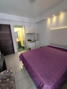 um quarto com uma cama roxa e uma cozinha em Villa Niki em Olympiakí Aktí