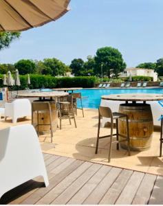 een patio met tafels en stoelen naast een zwembad bij Cala Rossa by Saraï, Apt T2 4 personnes, dans Résidence hôtelière avec piscine in Lecci