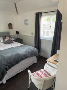 um quarto com uma cama, uma janela e uma cadeira em The Gatehouse em Long Melford