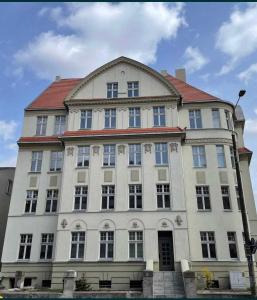 un gran edificio blanco con techo rojo en Apartamenty In Centro by 3 maja en Gniezno