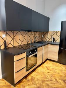a kitchen with black counter tops and wooden cabinets at Apartamenty In Centro by 3 maja in Gniezno