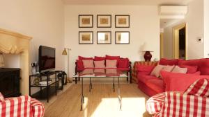 a living room with red couches and a tv at Penthouse w/ unique harbour view in Valletta
