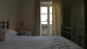 Schlafzimmer mit einem Bett und einem Fenster in der Unterkunft Penthouse w/ unique harbour view in Valletta