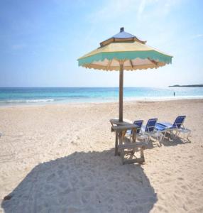 dos sillas y una sombrilla en una playa en Je Suis Content - 4 Bed 4 B-r Beachfront Villa W-staff, en Duncans
