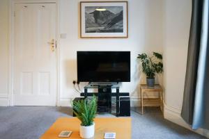 a living room with a flat screen tv on a table at Brixham Ground Floor Apartment in Torquay