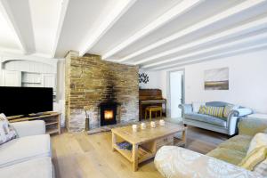 a living room with a couch and a fireplace at Tabbs Cottage - Close To Salcombe and Beaches in Malborough