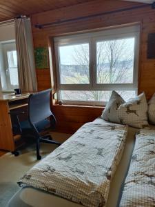 a bedroom with a bed and a desk and a window at Sunwood Apartment-Ferienwohnung mit Herz in Finkenstein