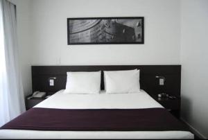 a bedroom with a large bed with two pillows at Apartamento Completo ao lado da lagoa da Pampulha in Belo Horizonte