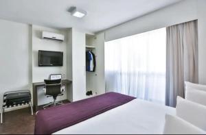 um quarto com uma cama, uma secretária e uma televisão em Apartamento Completo ao lado da lagoa da Pampulha em Belo Horizonte