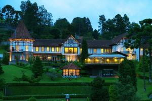 a large house with lights on in the yard at Hotel Vila Inglesa in Campos do Jordão