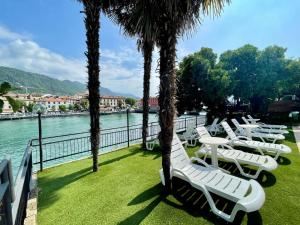 een rij witte ligstoelen naast het water bij Hotel Stazione sul lago di Iseo in Paratico