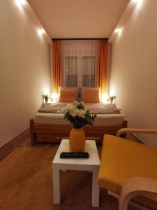 1 dormitorio con 1 cama y un jarrón de flores sobre una mesa en Római 1, en Dunaújváros