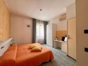 パラーティコにあるHotel Stazione sul lago di Iseoのベッドルーム1室(オレンジ色の毛布付きのベッド1台付)