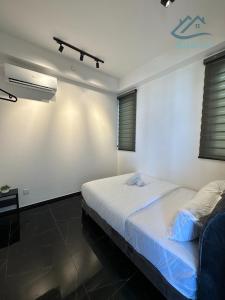 Cette chambre blanche dispose d'un lit et d'une fenêtre. dans l'établissement Urban Suites Georgetown by BNB4U, à Jelutong