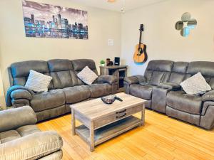 sala de estar con sofás de cuero y mesa de centro en Bright, Stylish & Cozy 2Bed Unit w/Backyard & Grill Close to NYC!, en Haledon
